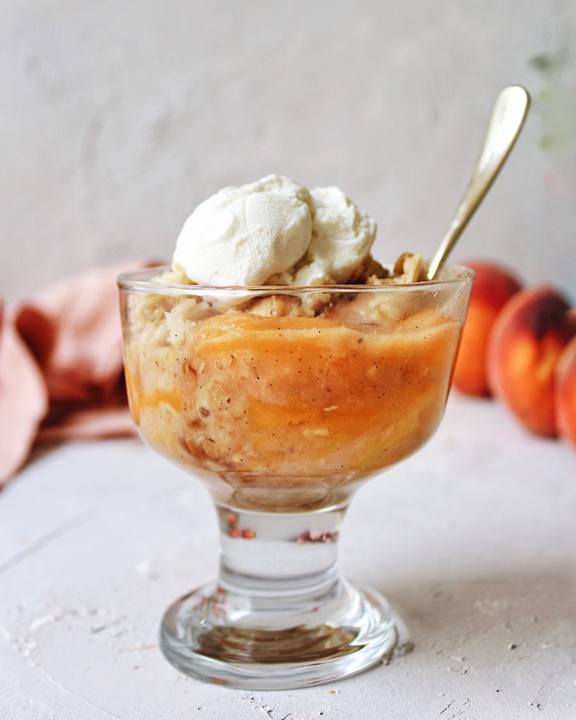 Single serving of ginger peach crisp in a glass bowl with a spoon