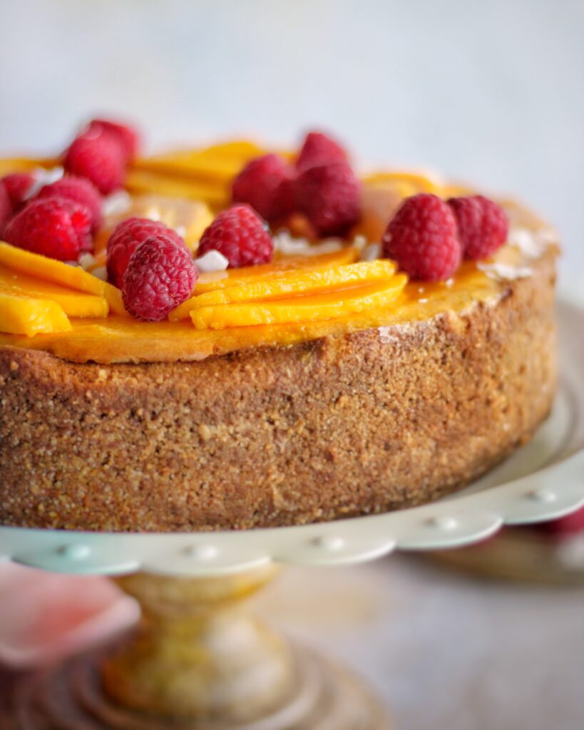 close up of mango coconut cheesecake showing detail of coconut graham cracker crust 