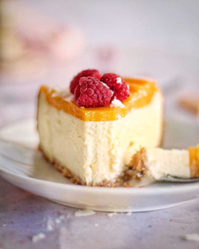 A zoomed in shot of a slice of mango coconut cheesecake 